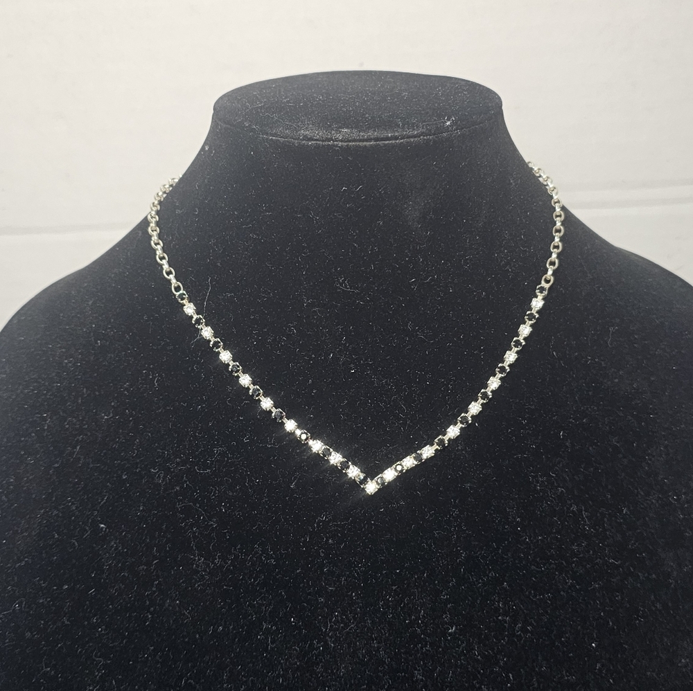 Elegant V-shaped tennis necklace features a sophisticated bezel-set design